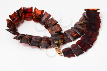 coiled necklace from polished faceted amber flat pieces on white paper background