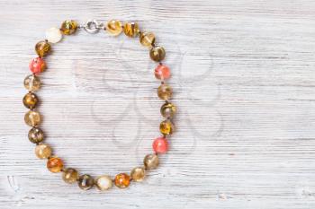 top view of faceted agate necklace on gray wooden board with copyspace