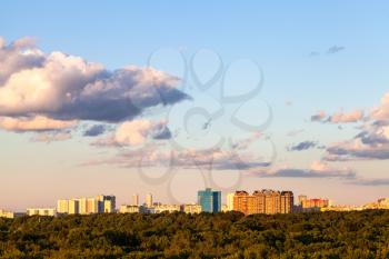 sunset blue and pink sky with and gray clouds over city and green forest in sunny summer evening