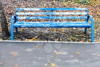 shabby blue wooden bench in city park on autumn day
