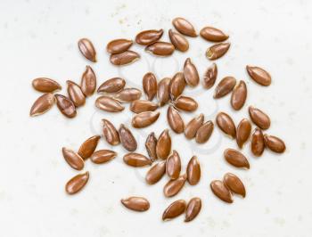 several brown flax seeds close up on gray ceramic plate