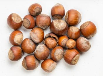 top view of pile of shelled and whole hazelnuts close up on gray ceramic plate