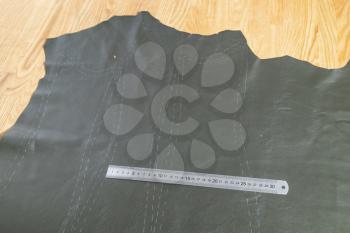 steel ruler on leather with drawn pattern at wooden table