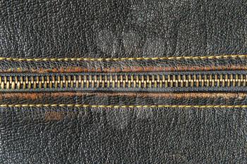 Metal zipper and black leather taken closeup as background.
