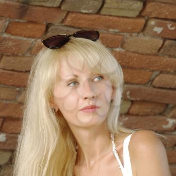 Beautiful blonde against old red brick wall taken closeup.