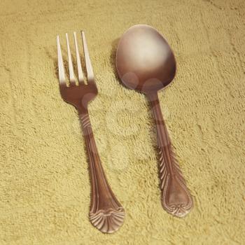 Metal cutlery on taupe fabric background taken closeup.