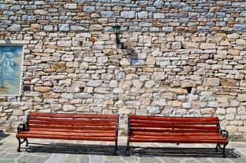 and stone pavement in the greece island of paros old bench near a brick antique wall 