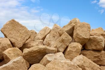Heap of large shapeless blocks of limestone against the background of blue sky