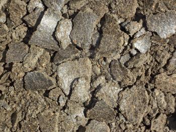 Shapeless pieces of oil cake in the heap close up. It is used as feed for animals, birds and fish