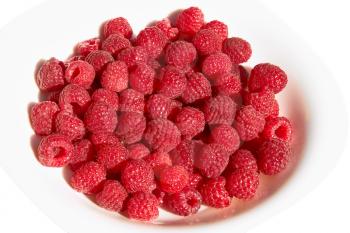 Lots of ripe red raspberry berries on a plate over white background close up