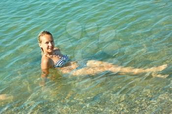 Teen girl on the turquoise sea water surface in shallow coastal area