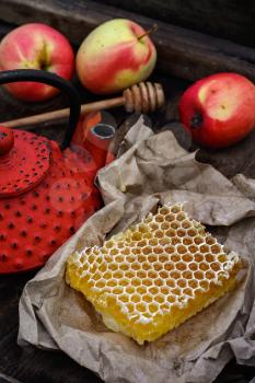 Honeycomb wrapped in grey paper on the background of the red kettle