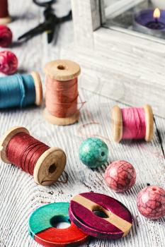 Beads and spools of thread for needlework on bright background