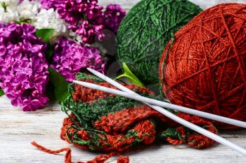 Balls of wool yarn for knitting and branches of lilac blossoms