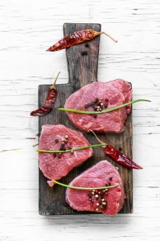 Three raw veal steak with peppers and spices