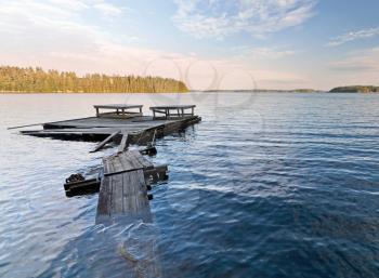 Empty old wet wooden pier on the Saimaa lake coast