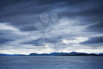 Dark blue stormy clouds over the coastal rocks. Empty Norwegian sea landscape