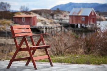 Red wooden chair in small Norwegian  village on the sea coast