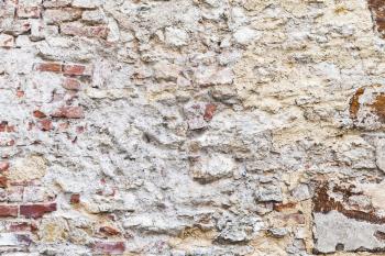 Old brick wall with damaged yellow stucco layer, flat background photo texture