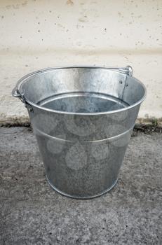 Shiny steel empty bucket stands on concrete floor