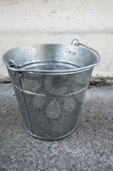 Empty bucket stands on concrete floor, outdoor photo