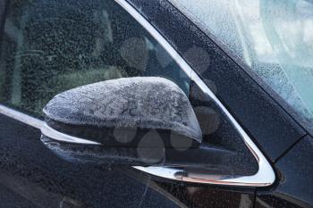 SUV car mirror covered with fresh frost in cold winter season