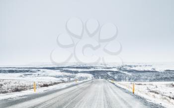 Icelandic road covered with ice and snow, empty rural landscape