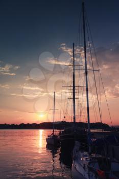 Vertical silhouette photo of sailing ship moored in port of old Nesebar at sunset, Bulgaria
