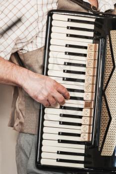 Live music background. Accordionist plays vintage accordion. Close-up vertical photo with selective focus