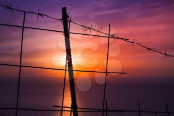 Barbed wire fence with colorful sunset on a background. Landscape of Greek island Zakynthos