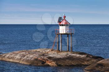 Traditional Norwegian lighthouse tower with solar battery and conical red top