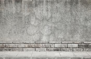 Abstract architectural background. Gray grungy concrete wall and tiled road pavement