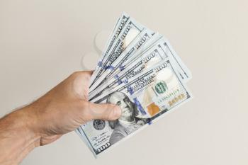 Fan of 100 Dollars notes in male hand over gray wall background