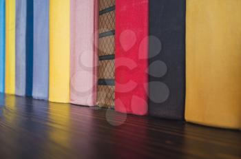Books in colorful covers stand on wooden shelf