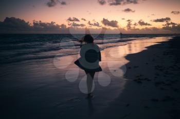 Silhouette photo of a girl walking on Atlantic Ocean coast in early morning. Dominican Republic, Bavaro beach