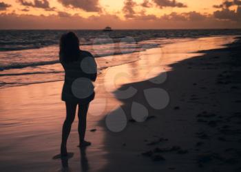 Silhouette photo of a girl standing on Atlantic Ocean coast in early morning. Dominican Republic, Bavaro beach