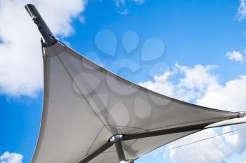 Awning in sail shape under cloudy sky background