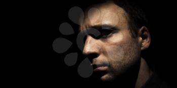 Closeup studio portrait of young European man isolated over black background, low key photo