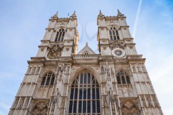 Westminster Abbey main facade under blue cloudy sky. One of the most popular landmarks of London, United Kingdom