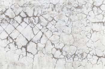 Old concrete wall with cracked white paint layer, background photo texture 