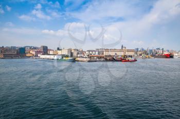 Port of Naples, coastal cityscape with cargo ships under bright cloudy sky