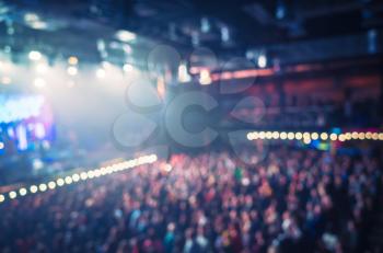 Blurred photo background, life music concert hall with colorful illumination and crowd of people