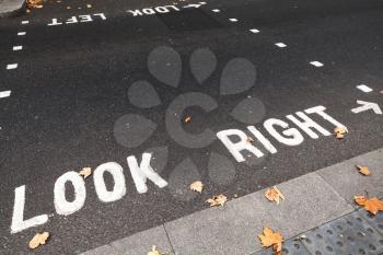 Caution road marking for pedestrians shows direction of approaching traffic in London