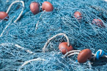 Blue fishing net with red floats lays in port. Close-up background photo with selective focus