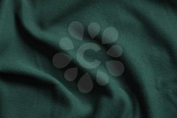 Texture of dark green fleece, soft napped insulating fabric made from polyester, wavy pattern