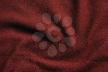 Texture of red fleece, soft napped insulating fabric made from polyester, wavy pattern