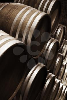 Wine storage. Round wooden barrels in dark winery, close-up vertical photo with selective focus