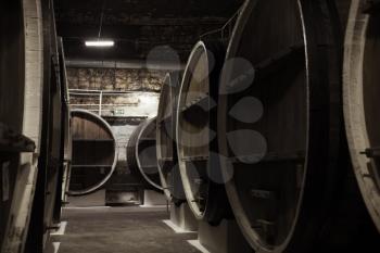 Vintage wooden barrels in dark winery basement, close up photo with selective focus