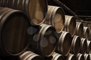 Wooden barrels in dark wine factory hall, close up photo with selective focus