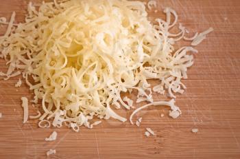 Pile of fresh grated cheese on wooden table